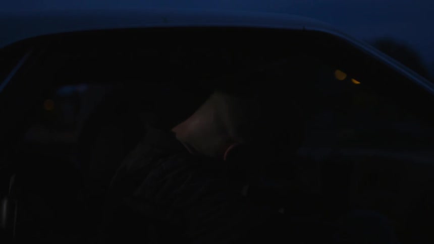 A man enters a car at night