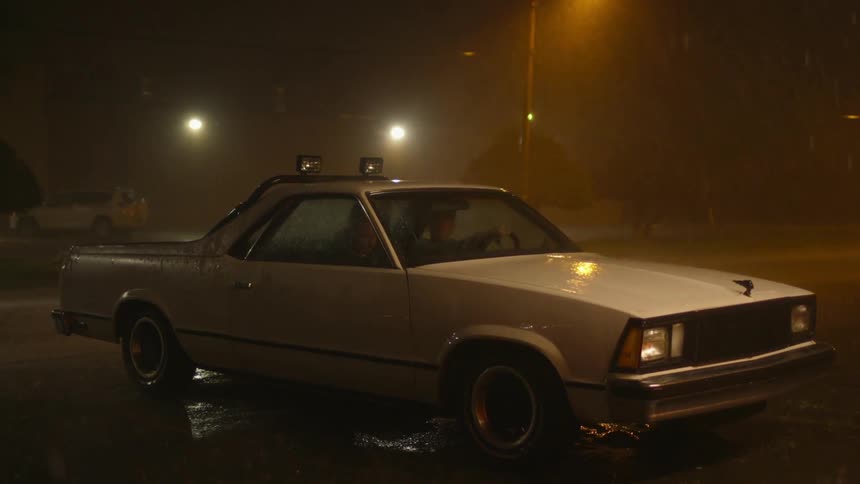 Two people sit in a car in the rain