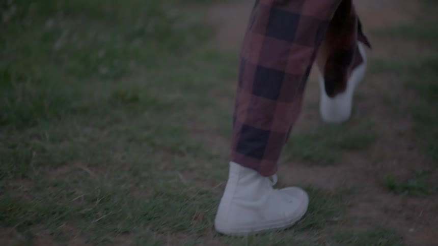 A person walks along the grass filled field
