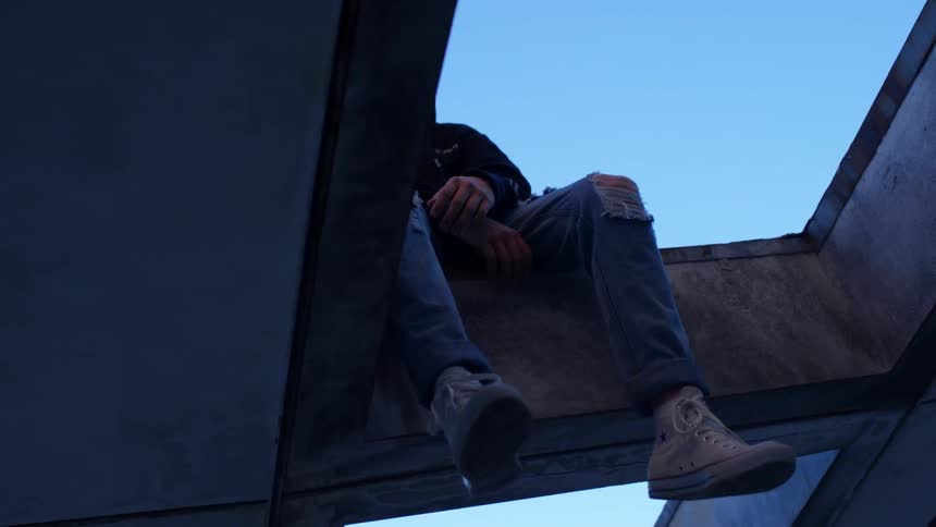 A man hangs with his feet over a steel beam