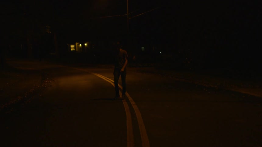 A person is walking down the middle of a road at night