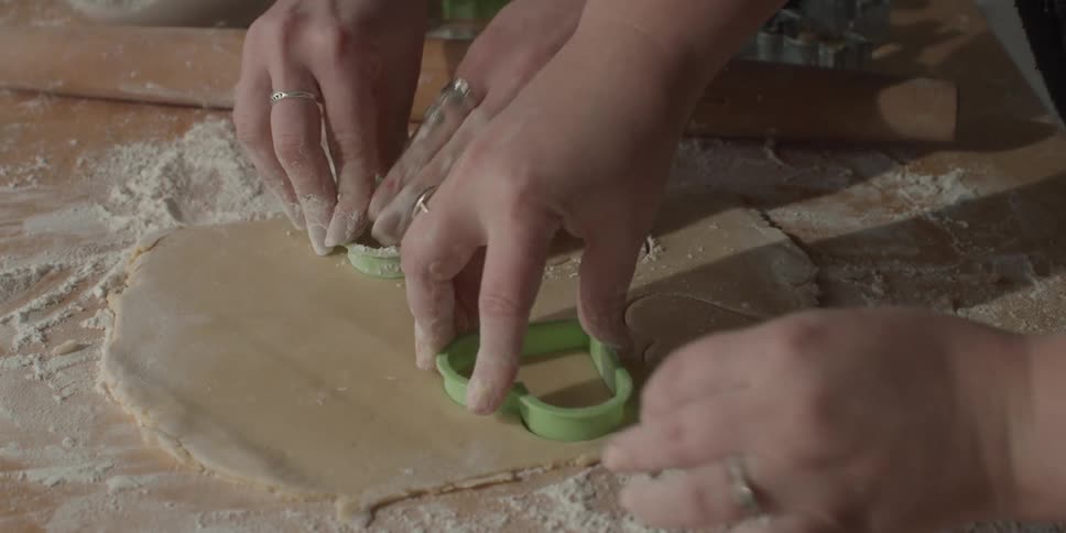 People are cutting heart shaped cookies out of dough together