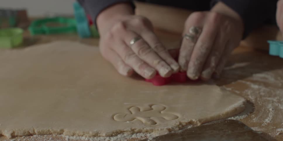 People are cutting cookies from a sheet of dough
