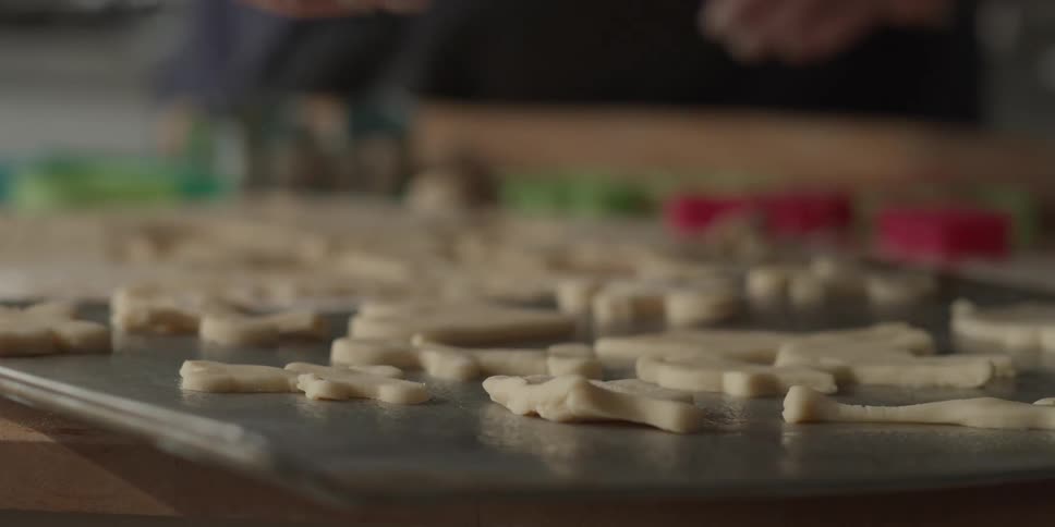 Woman places raw cookies on a baking sheet