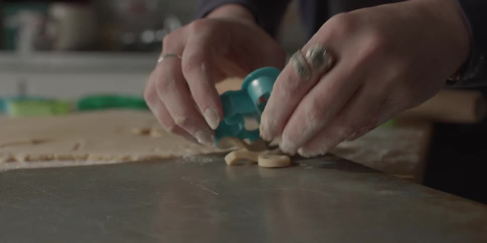 A woman makes gingerbread men out of cookie dough