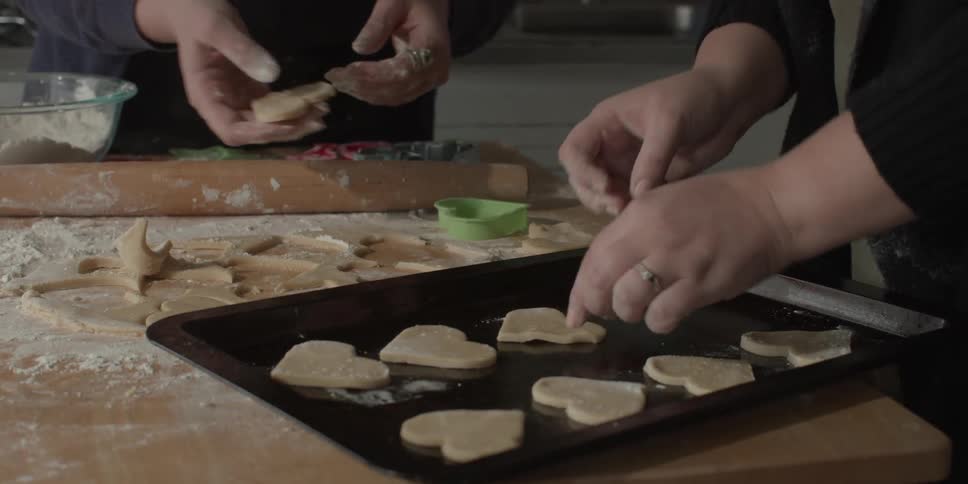 Women press shaped cookie dough pieces