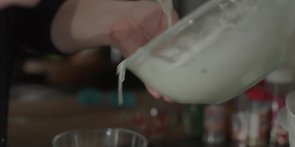 A woman pours batter into cups