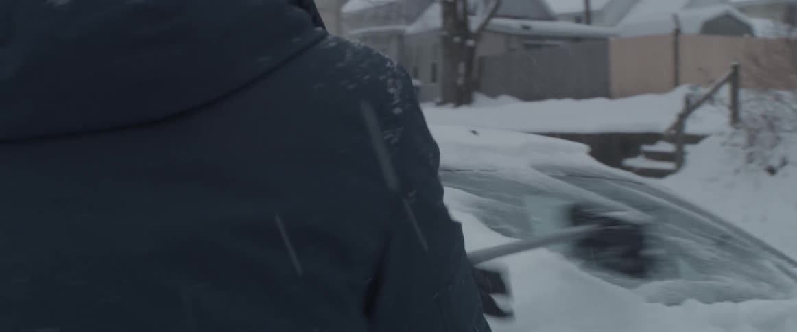 A man is clearing the snow off of his car