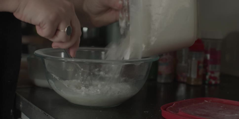 A woman stirs flour into a mixing bowl