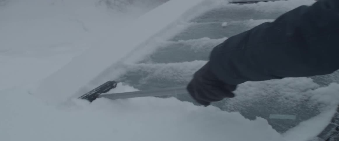 A man scrapes the snow off of his car