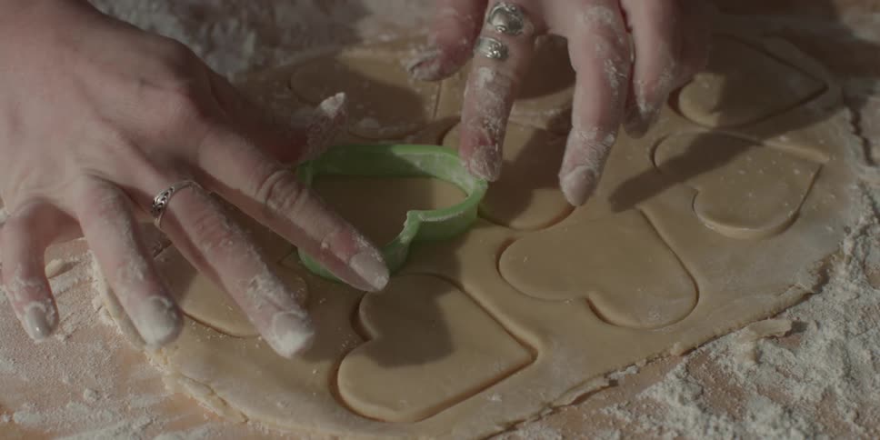 A woman presses heart shaped cookie dough