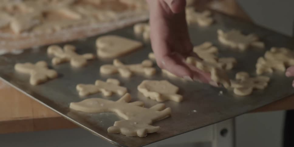 A woman places shaped cookie dough on a sheet