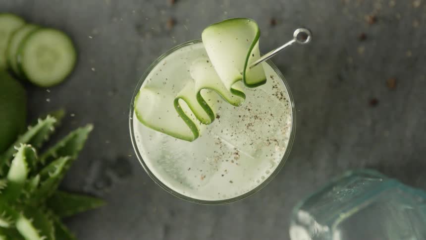 A person sprinkles pepper onto a garnished drink