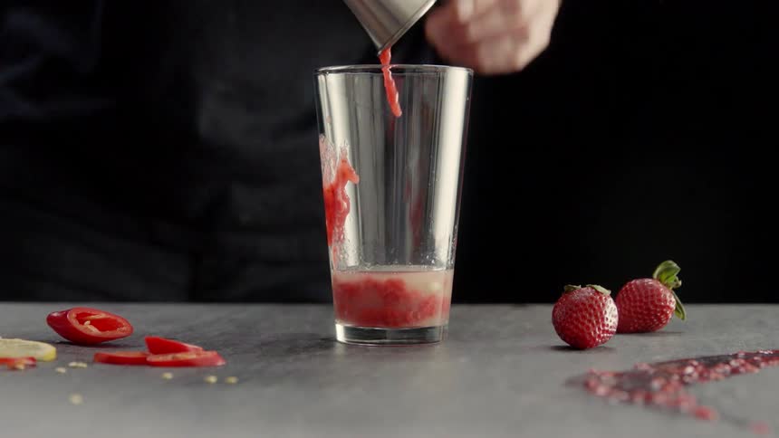 A man pours fruit puree into a glass