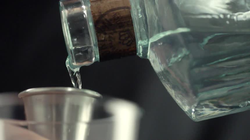 Someone pours liquid into a small metal cup