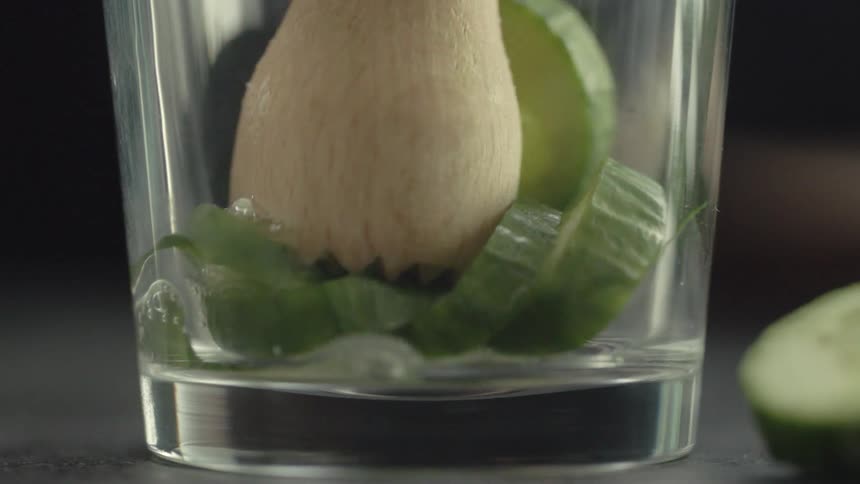 Wooden utensil squeezes juice out of a vegetable while in a glass