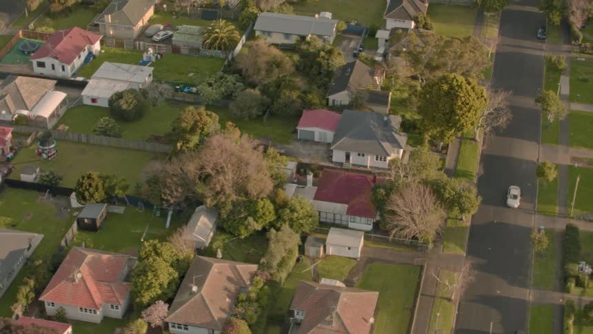 Car travels down a street past some houses