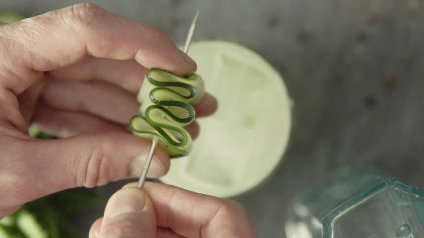 A person skewers a slice of cucumber