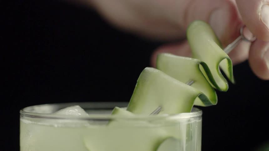 A person places garnish into a cocktail