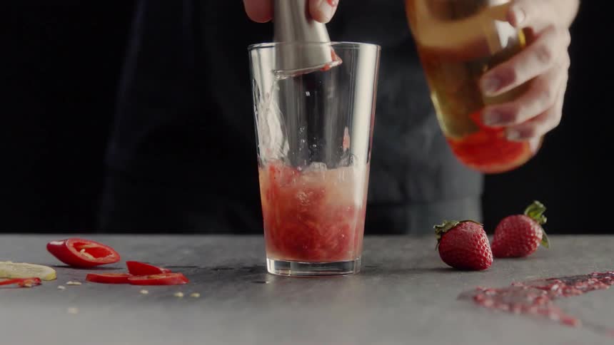 A person is mixing a drink with fruit and water