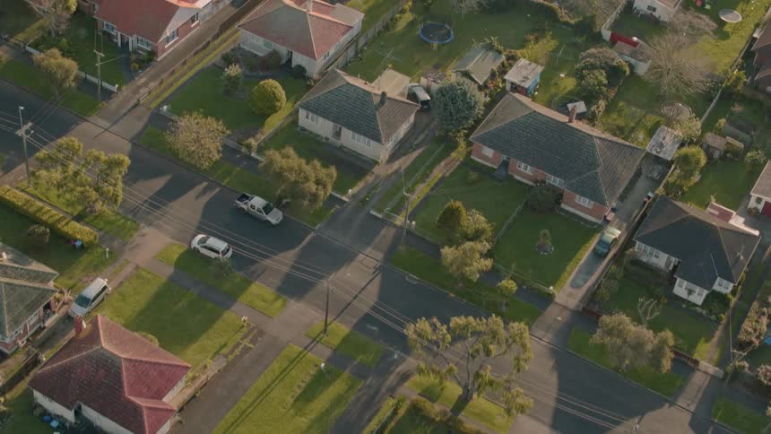 A car drives down the street in this neighborhood on a sunny day