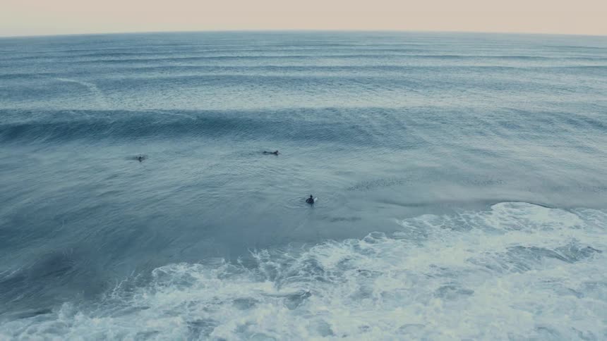 Surfers ride over waves as they paddle out