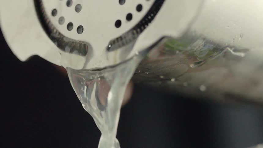 A person is pouring a mixed drink from a shaker