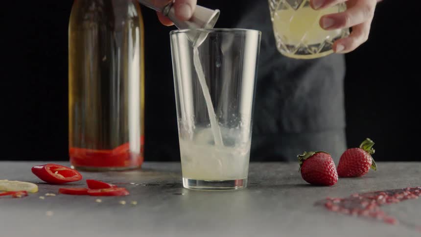 A person is preparing mixed drinks with fruit