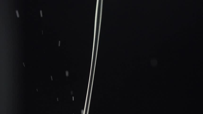 A stream of water is being poured and drops of water are flying up