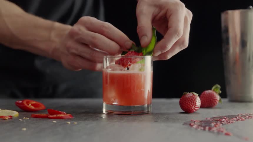 A man is preparing a drink with strawberries on top