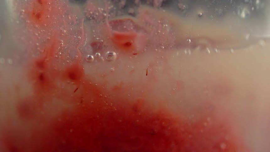 Strawberry is splashed into a glass of liquid