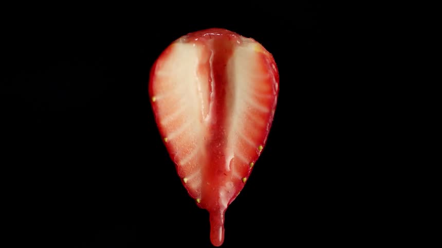 A strawberry drips red liquid below