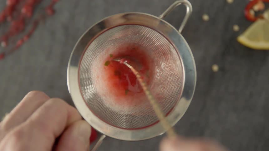 A person stirs liquid in a sieve