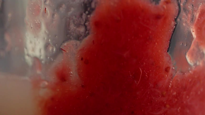 Chunky red liquid is poured into a glass