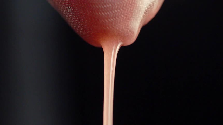 Pink liquid is filtered through a sieve