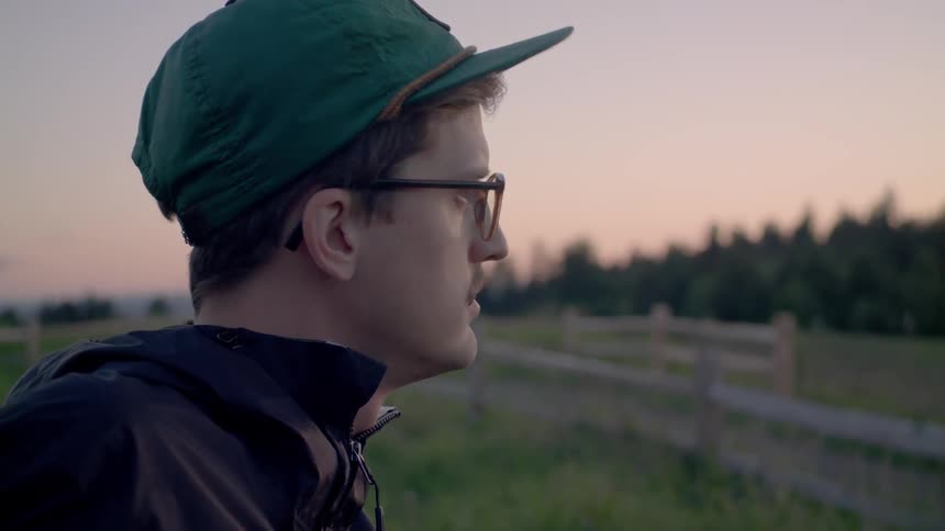 A man chews gum and looks out over the forest at dawn