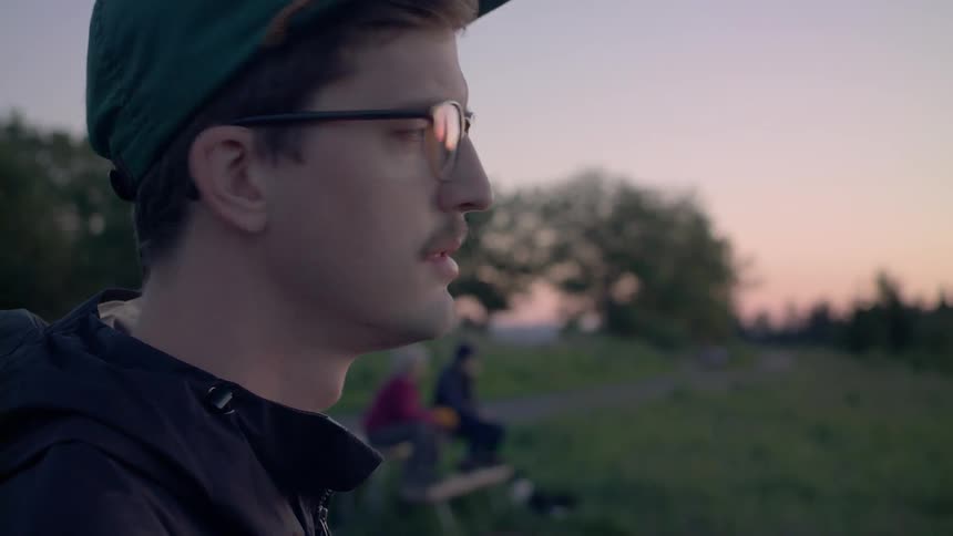 A man looks back and forth over at sunset in the park
