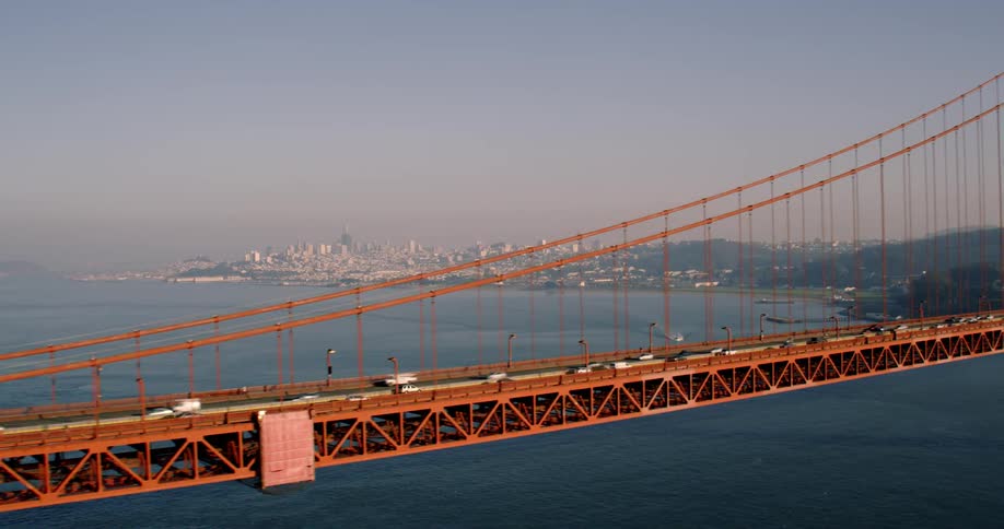The long bridge has cars traveling to the city; Golden Gate