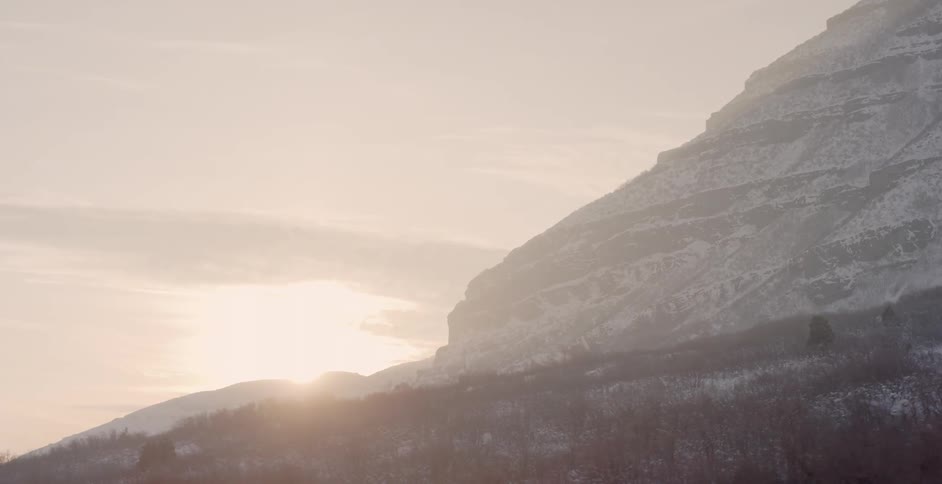The mountain is tall and the sun is setting behind it