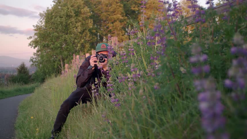 A man takes a picture in a field of purple flowers