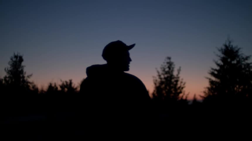 Man walks near the trees while carrying a bag over his shoulder