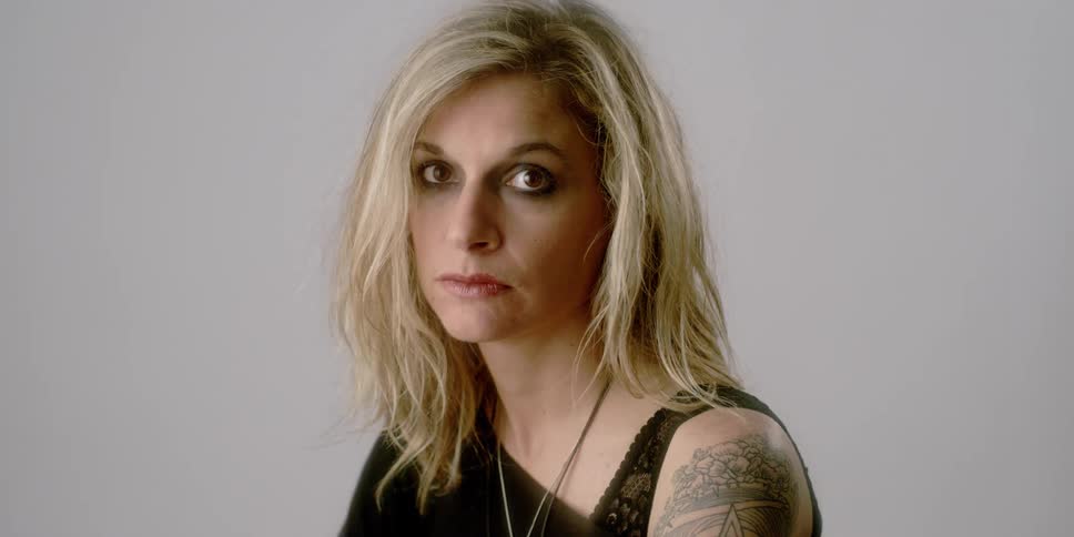 A woman shifts her gaze toward the camera and leans back