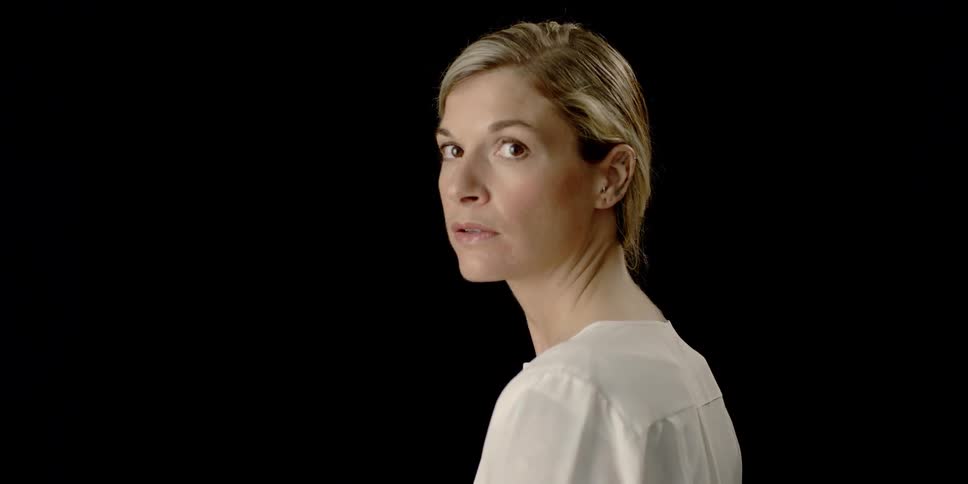 A woman looks over her shoulder and blinks