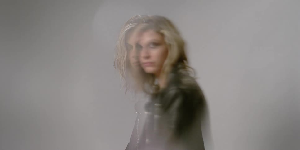 A woman wearing a black leather jacket sits and looks