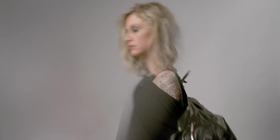 A woman puts a black leather jacket on