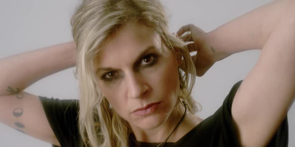 A woman is staring at the camera and pulling her hair back