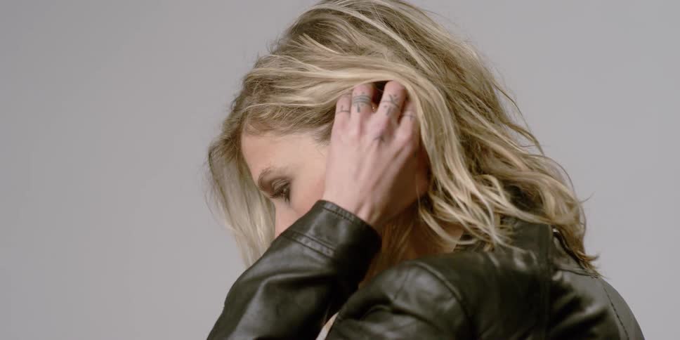 A woman pushes her hair back