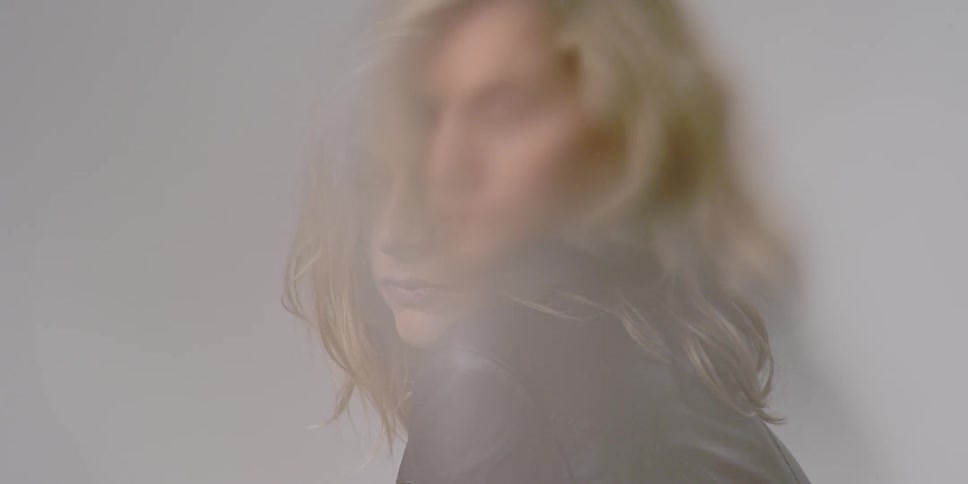 A woman looks across her shoulder then adjusts her hair