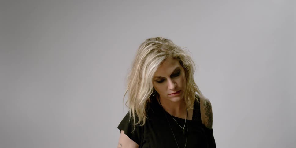 A blonde haired woman brushes her hair back