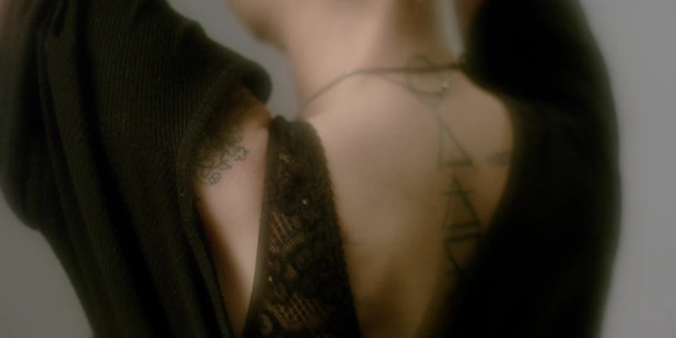 A woman with tattoos is putting her hair up and stretching her neck